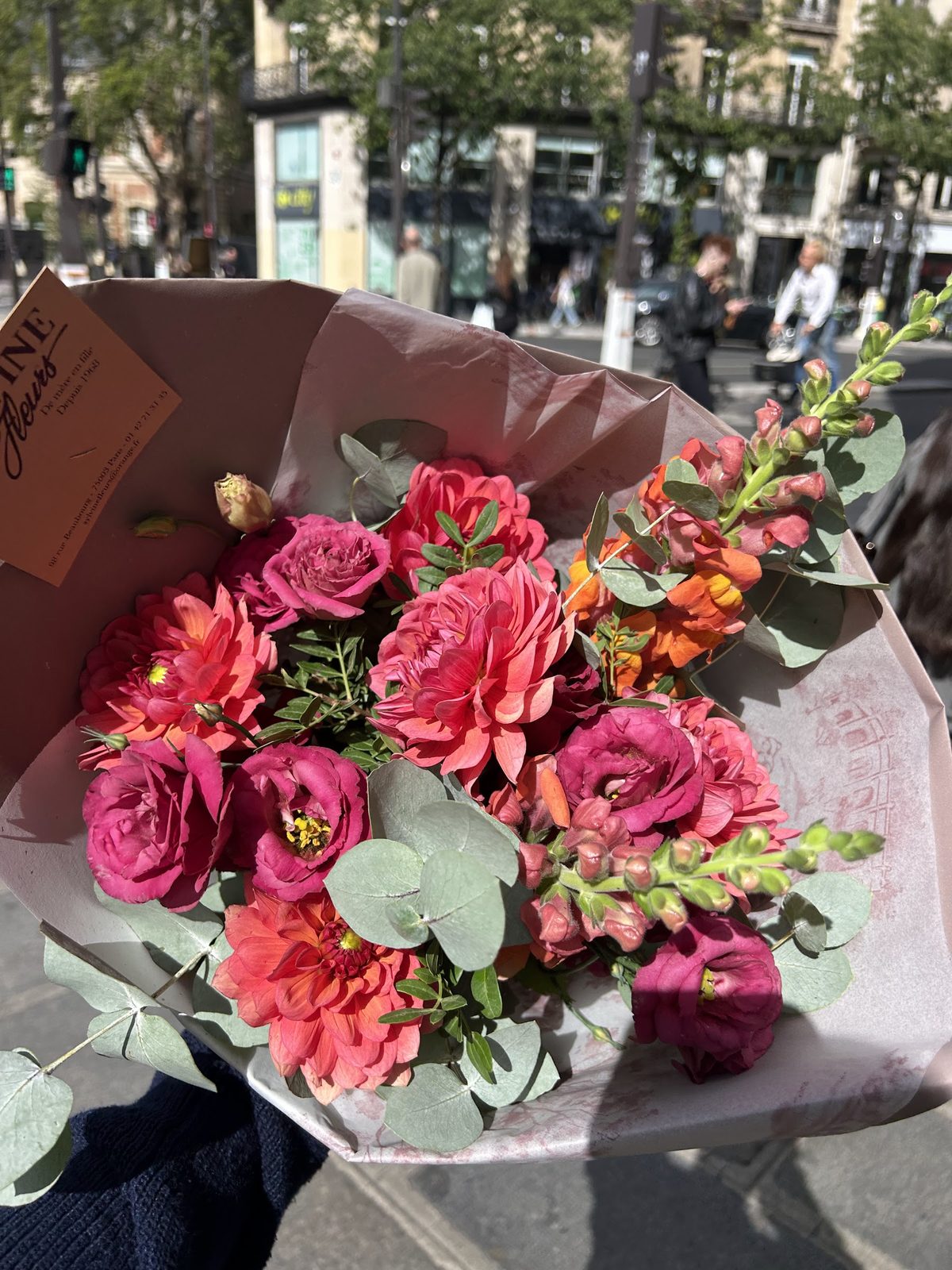 Bouquet corail et rose tenu à la main devant la boutique