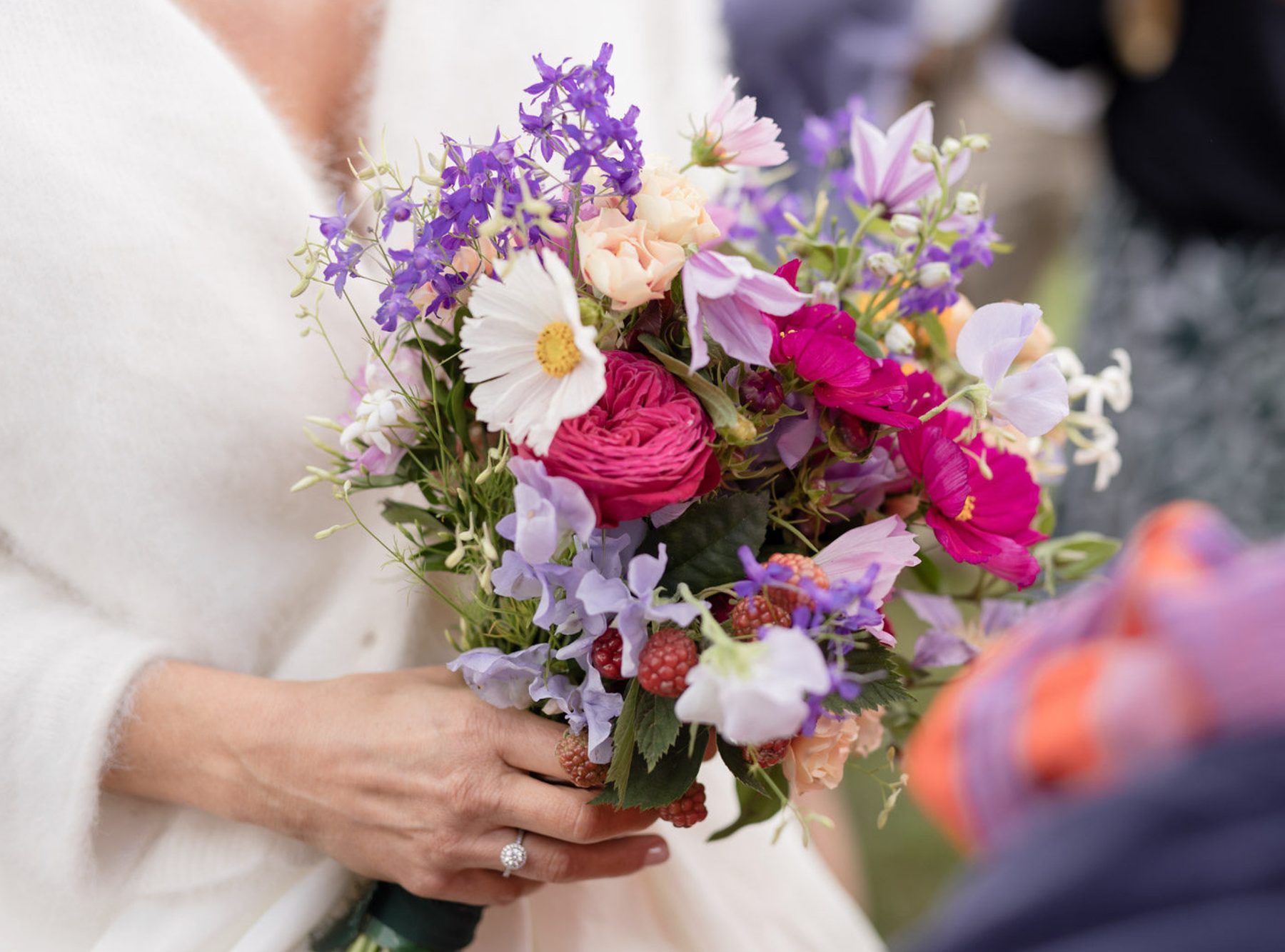 Bouquet de mariée aux tons roses et violets, tenu par la mariée